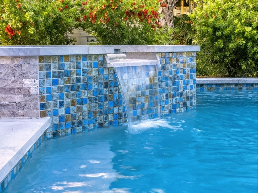 luxury backyard pool with waterfall feature and tropical landscaping