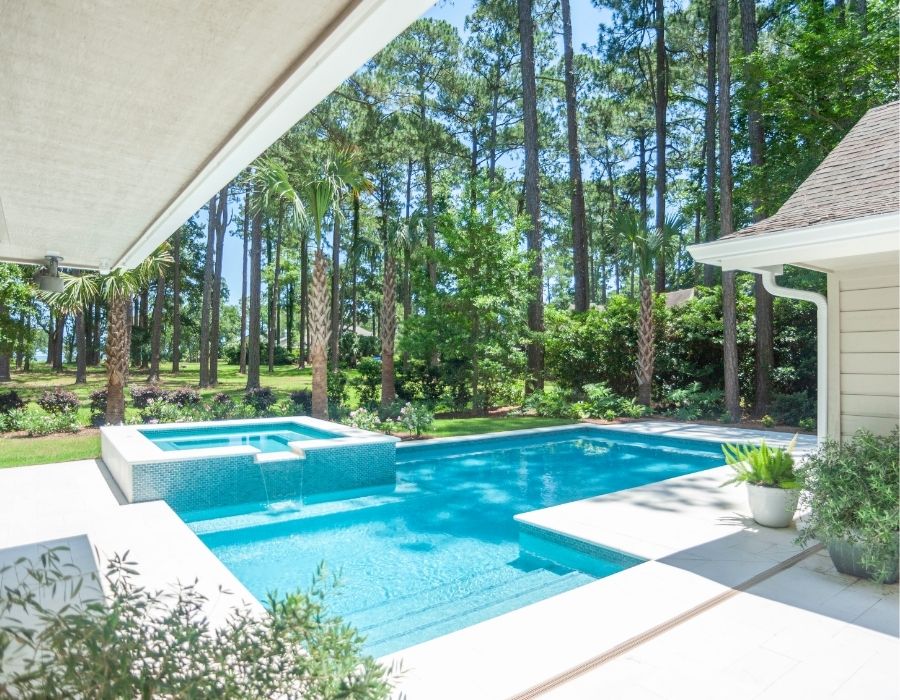 Modern backyard pool and spa with forest view and sleek patio design