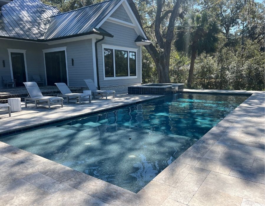  backyard pool features a modern, minimalist design with clean lines, sleek tile decking, and cozy lounge seating—perfect for relaxing by the water while enjoying the peaceful natural surroundings