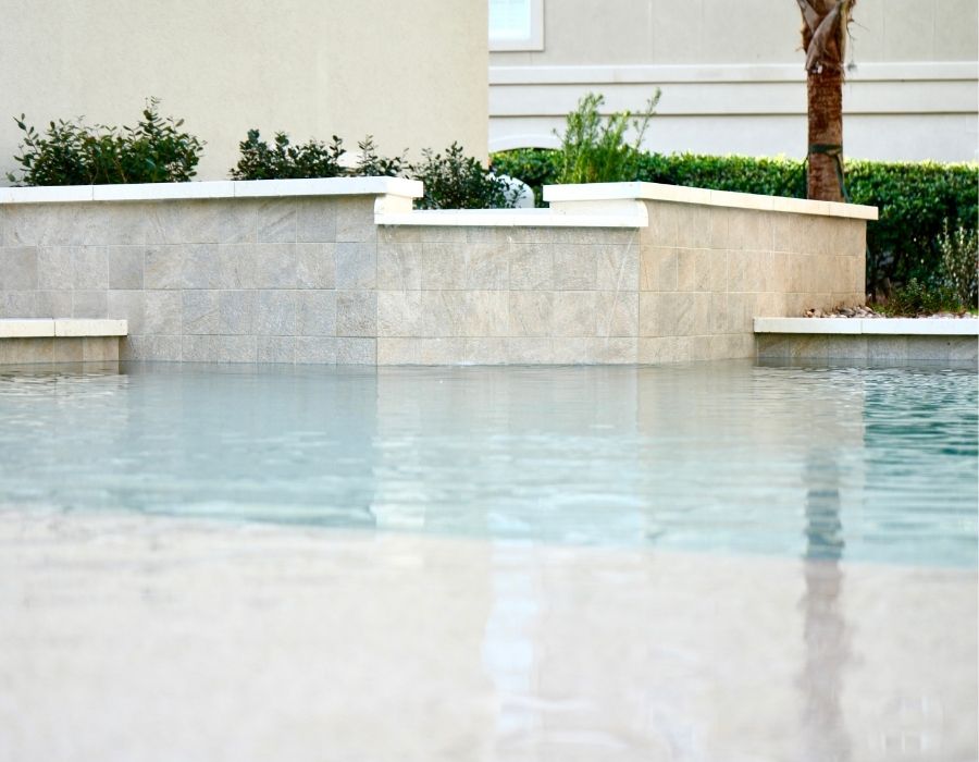 modern pool features sleek stone walls and clean lines, with a shallow, reflective water surface that gives it a serene, spa-like ambiance—perfect for both relaxation and elegant outdoor aesthetics