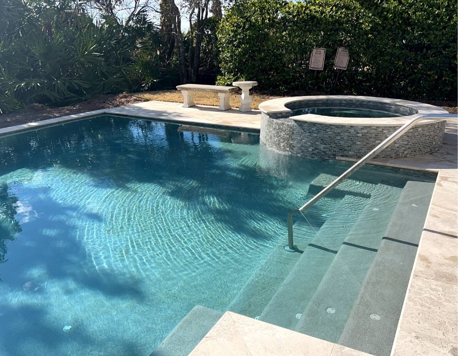 With its soft-toned stone tile, shimmering water, and elevated spa spilling gracefully into the pool, this serene setup creates a soothing, resort-style atmosphere perfect for unwinding in luxury right at home